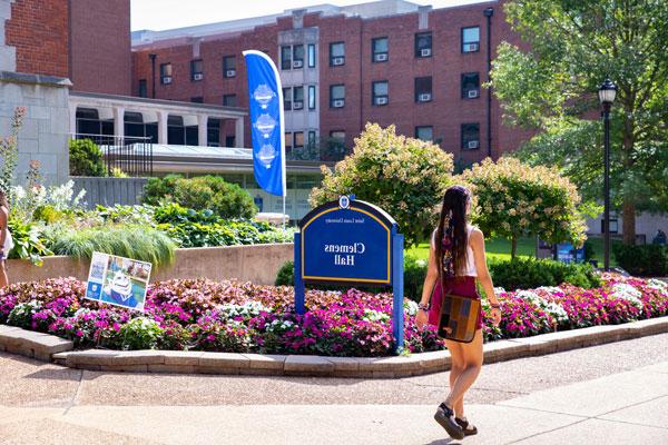 Student walking in front of Clemmon's Hall on 博彩网址大全's campus